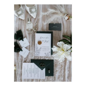 Elegantní svatební flatlay s botami, parfémem, šperky, prstýnky a svatebním oznámením Dominika & Josef s květinovým motivem.